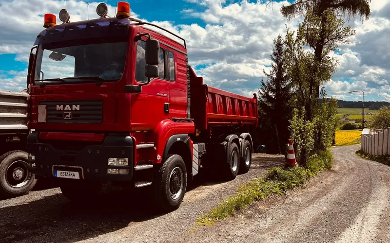 Červené nákladné vozidlo – sklápač na poľnej ceste
