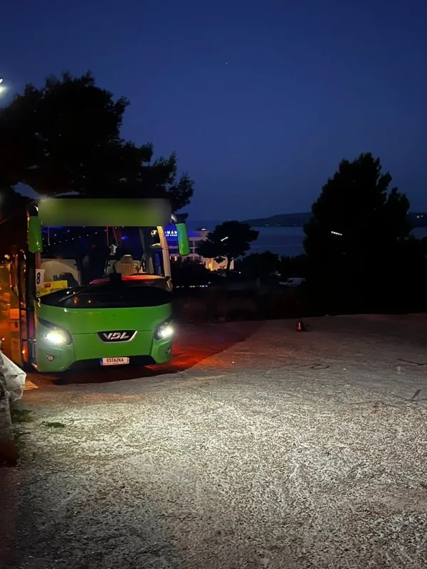 Autobus s rozsvietenými svetlami za súmraku